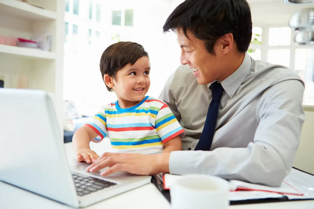 A father and his young son smiling at a laptop together